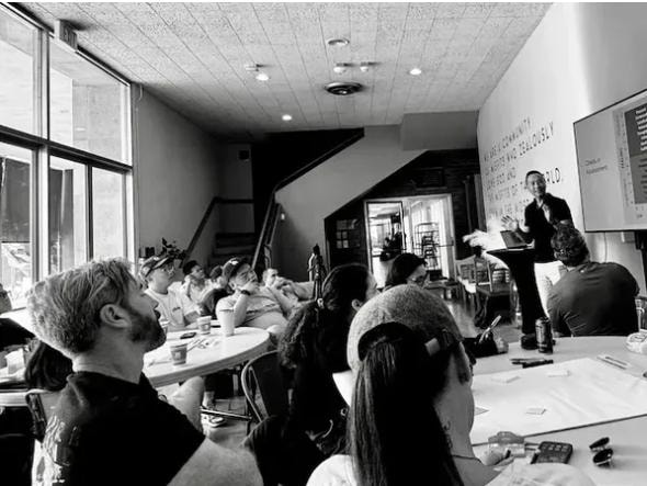 Workshop seminar with participants seated at tables facing a presenter